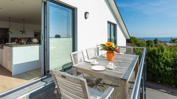 A modern outdoor dining area with a table, chairs, and a vase of flowers. - Villa am Kreidebruch, FeWo OstseeWeitblick - panoramic view of the Baltic Sea (Sassnitz auf Rügen)