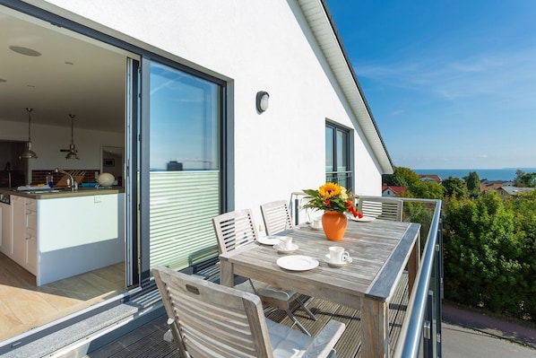 A modern outdoor dining area with a table, chairs, and a vase of flowers. - Villa am Kreidebruch, FeWo OstseeWeitblick - panoramic view of the Baltic Sea (Sassnitz auf Rügen)