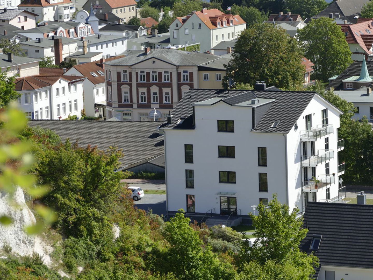 Ein mehrstöckiges Gebäude mit flachem Dach, großen Fenstern und einem Balkon im oberen Stockwerk.
