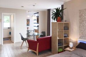 Ein modernes Wohnzimmer mit einem Glastisch, einem roten Sofa und einem Bücherregal.