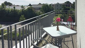 A balcony with a table and chairs, a railing, and a view of the sea and buildings. - Apartment Richi - central and quiet in the harbor town of Sassnitz - (Sassnitz auf Rügen)