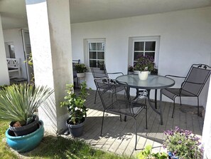 A patio with a round table and four chairs, surrounded by potted plants and a white wall. - Villa Johanna, App.1 - Bathing villa with magnificent sea view - Villa Johanna, (Sassnitz auf Rügen)