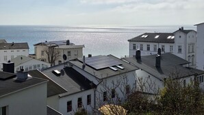 Uma cidade costeira com edifícios, alguns com painéis solares, e vista para o mar.
