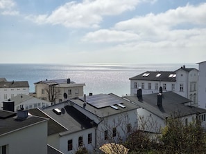 Eine Küstenstadt mit Gebäuden, einige davon mit Solaranlagen, und Blick aufs Meer.