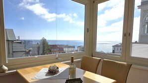 Um quarto com uma mesa, uma cadeira, uma garrafa e um letreiro com a palavra 'Wilkommen'.