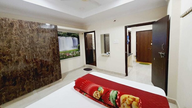 Un dormitorio con cama, armario, espejo y puerta que da a otra habitación.