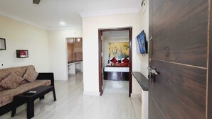 Una sala de estar con sofá, ventilador de techo, televisor y armario.