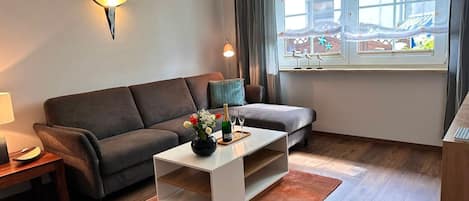 Un salon moderne comprenant un canapé, une table basse, une lampe et donnant sur un balcon avec une balustrade.