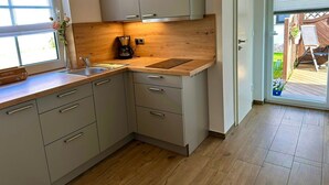 A modern kitchen with wooden countertops, a coffee maker, and a view of the outdoor deck. - Vacation apartment Seestern - Holiday apartment Seestern in Sassnitz on Rügen with (Sassnitz auf Rügen)