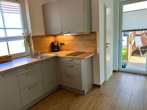 Eine moderne Küche mit Holzarbeitsplatten, einer Kaffeemaschine und Blick auf die Terrasse.
