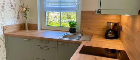 Una cocina con ventana, pileta, encimera y cafetera.