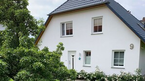 A two-story house with a white facade, a dark roof, and a small garden with roses. - Vacation apartment Seestern - Holiday apartment Seestern in Sassnitz on Rügen with (Sassnitz auf Rügen)