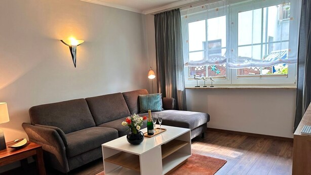A modern living room with a sofa, a coffee table, a lamp, and a view of a balcony with a railing. - Vacation apartment Seestern - Holiday apartment Seestern in Sassnitz on Rügen with (Sassnitz auf Rügen)