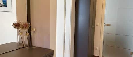 Una habitació amb un armari fosc, una porta i un quadre amb marc a la paret.
