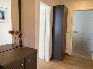 Ein Zimmer mit einem dunklen Schrank, einer Tür und einem gerahmten Bild an der Wand.