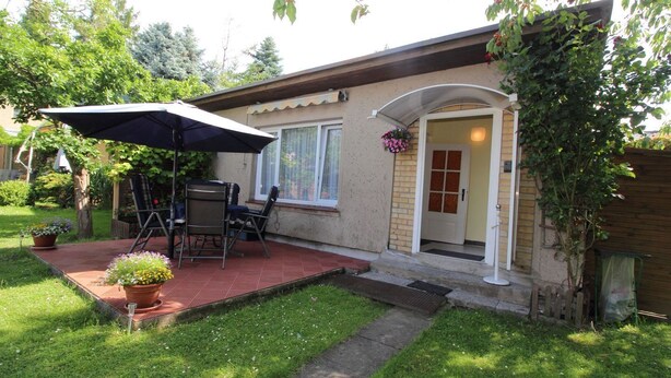 Une maison avec un patio, une porte et un petit jardin.