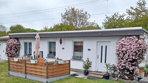 A single-story house with a front porch, a small deck, and a garden area with potted plants. - Vacation home Figelski with terrace in Sassnitz - Holiday home Figelski in Sassnitz (Sassnitz auf Rügen)