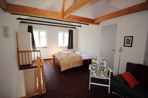 Ein Zimmer mit Bett, Sessel, Sofa, Schreibtisch und Fenster.