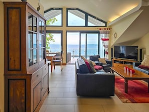 A spacious living area with a large TV, a sofa, and a dining table. - Villa Friede-Marie, Penthouse Lenea - magnificent sea view over the Baltic Sea - (Sassnitz auf Rügen)