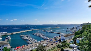 Uma marina com barcos atracados, um cais e um edifício com telhado plano.