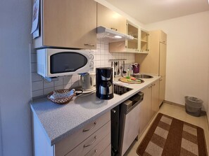 Eine kleine Küche mit Mikrowelle, Kaffeemaschine und Spüle.