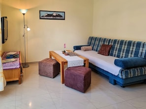 Ein Wohnzimmer mit einer Couch, einem Couchtisch, einer Lampe und einem gerahmten Bild an der Wand.