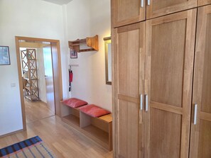 Ein Flur mit Holzschnitzschränken, einer Bank mit roten Kissen und einem Holzregal an der Wand.