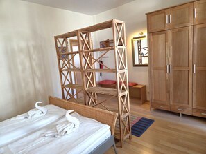 Ein Schlafzimmer mit einem Bett, einem Holzschrank, einem Spiegel und einer Holzwand.