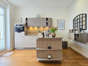 Eine moderne Küche mit integriertem Backofen, einer Kaffeemaschine und einer kleinen Kochinsel mit einer Uhr.