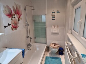 Ein Badezimmer mit Badewanne, Dusche, WC und einer Duschkabine aus Glas.