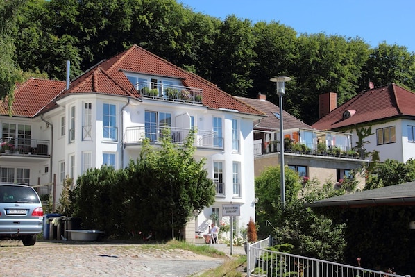 A multi-story building with balconies, a sign indicating a restaurant, and a parked car. - Vacation apartment Anemone - vacation with dog on the edge of the national park (Sassnitz auf Rügen)