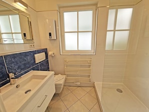A modern bathroom with a bathtub, a toilet, a shower, and a window. - Vacation apartment Anemone - vacation with dog on the edge of the national park (Sassnitz auf Rügen)