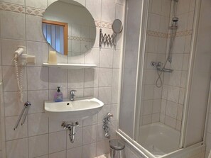 A bathroom with a sink, mirror, shower, and a telephone. - Fürstenhof, App. 202 - fantastic sea view and balcony - Fürstenhof, App. 202 - (Sassnitz auf Rügen)
