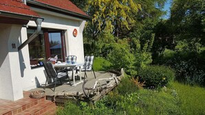 Una casa con patio, tavolo e sedie, e finestra con cornice rossa.