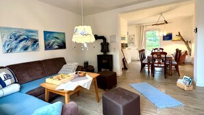 Un soggiorno con divano, tavolo in legno, camino, zona pranzo con sedie e opere d'arte alle pareti.