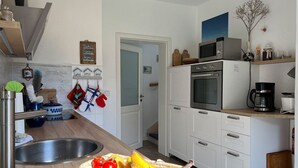 Una cucina con lavello, forno a microonde, forno e un cesto di frutta.