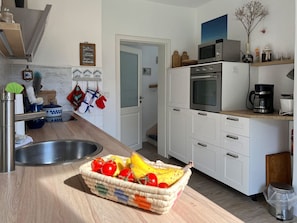 Eine Küche mit Spüle, Mikrowelle, Backofen und einer Fruchtkörbchen.