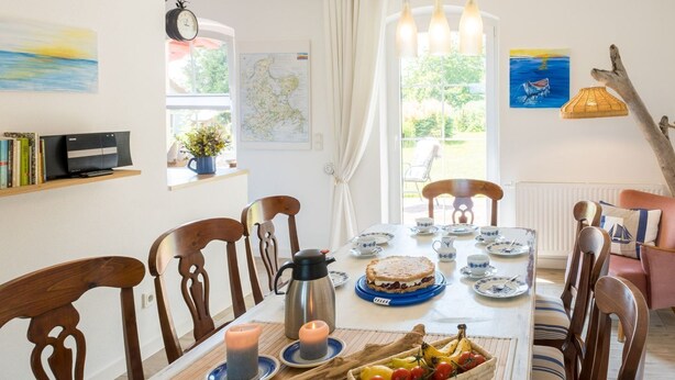 Una sala da pranzo con un tavolo di legno, sedie, una torta, frutta e servizi da tè.
