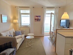 Une chambre d’hôtel avec un canapé, une petite table, un téléviseur et une vue sur l’extérieur.