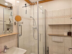 Ein modernes Badezimmer mit einer Duschkabine, einem Waschbecken und einem Spiegel.
