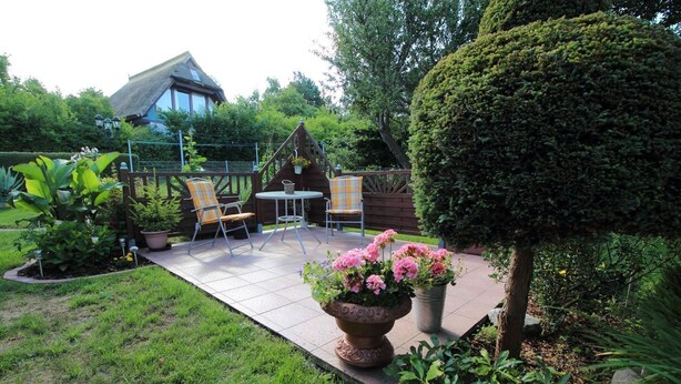 A patio with chairs and a table, surrounded by potted plants and a well-maintained lawn. - Vacation apartment near the Bodden - Holiday apartment near the Bodden - idyllic on the large (Glowe OT Polchow)