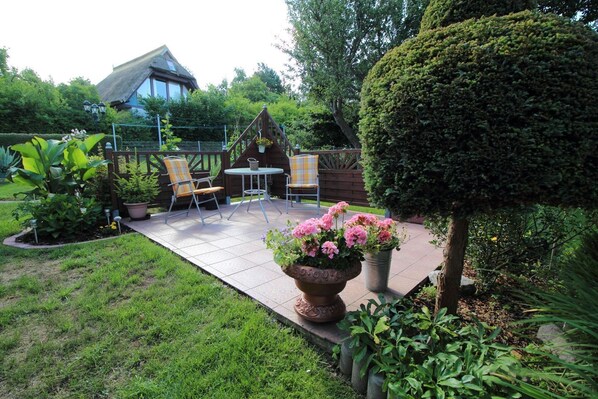 A patio with chairs and a table, surrounded by potted plants and a well-maintained lawn. - Vacation apartment near the Bodden - Holiday apartment near the Bodden - idyllic on the large (Glowe OT Polchow)