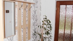 A room with a wooden wardrobe, a potted plant, and a door with a frosted glass panel. - Vacation apartment near the Bodden - Holiday apartment near the Bodden - idyllic on the large (Glowe OT Polchow)