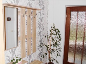 A room with a wooden wardrobe, a potted plant, and a door with a frosted glass panel. - Vacation apartment near the Bodden - Holiday apartment near the Bodden - idyllic on the large (Glowe OT Polchow)