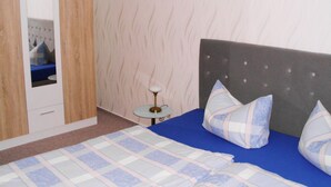 A bedroom with a bed, pillows, a bedside table, a mirror, and a wardrobe. - Vacation apartment near the Bodden - Holiday apartment near the Bodden - idyllic on the large (Glowe OT Polchow)