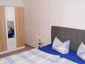 A bedroom with a bed, pillows, a bedside table, a mirror, and a wardrobe. - Vacation apartment near the Bodden - Holiday apartment near the Bodden - idyllic on the large (Glowe OT Polchow)