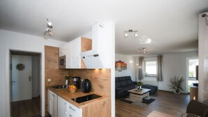 Een moderne keuken met witte kastjes, een houten aanrecht en een zwarte waterkoker.