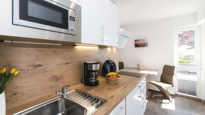 Een moderne keuken met een magnetron, koffiezetapparaat en een mand met fruit.