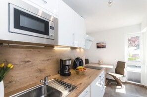 Eine moderne Küche mit Mikrowelle, Kaffeemaschine und Obstkorb.