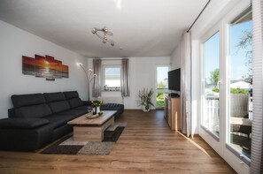 Ein modernes Wohnzimmer mit einer Couch, einem Couchtisch und einem Fernseher.